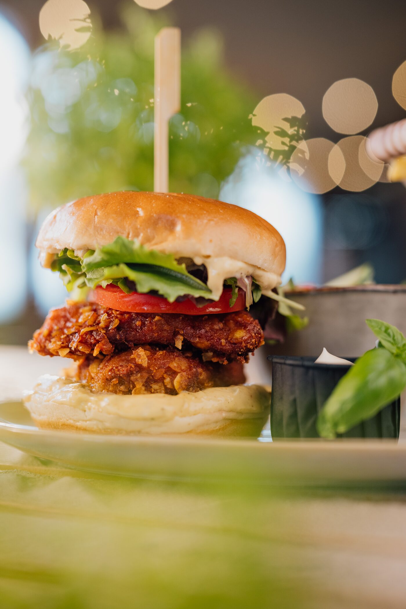 Chicken-Burger mit Tomate und Salat, warmes Innenlicht mit Bokeh