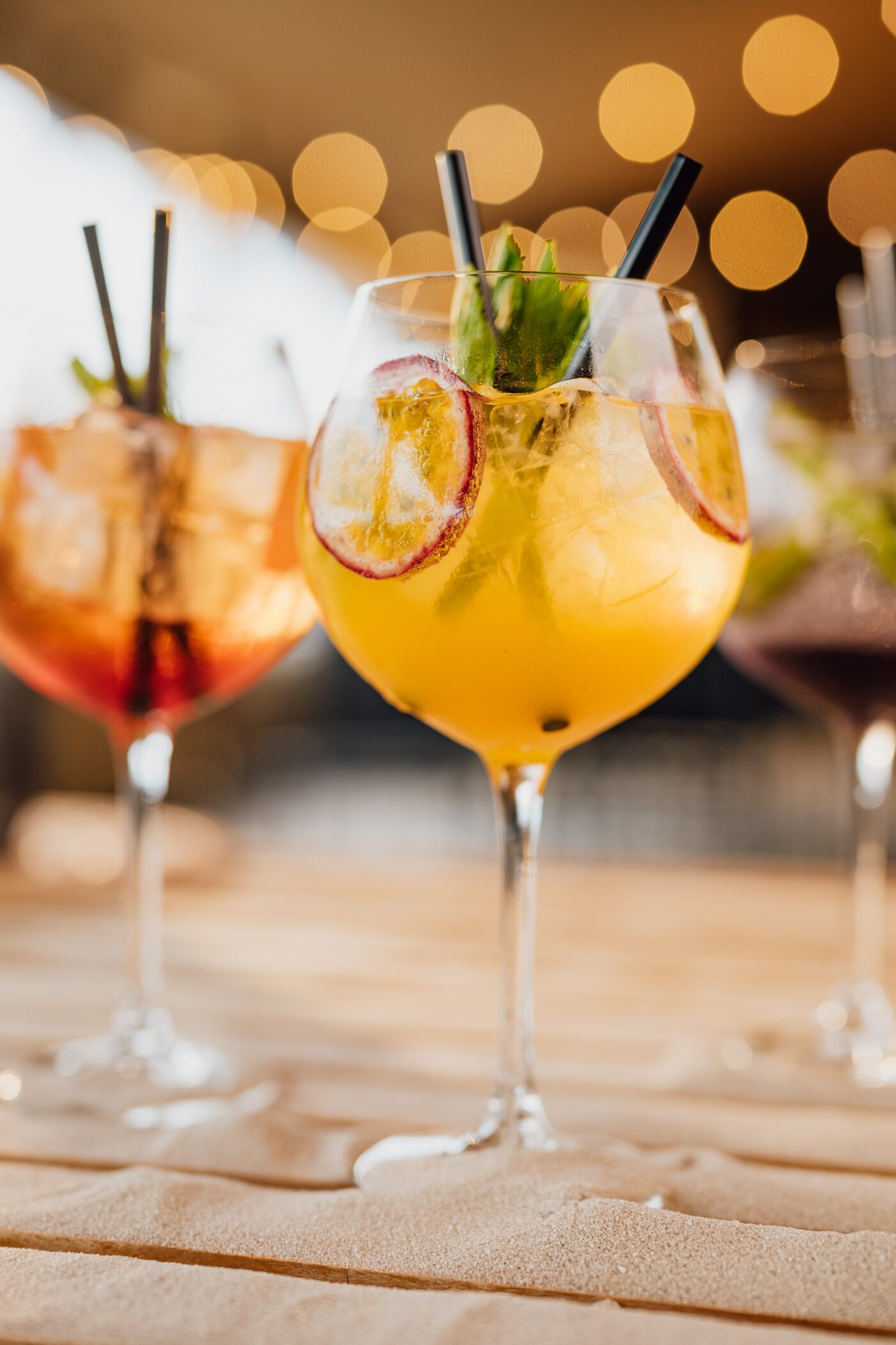 Drei Signature-Cocktails vor warmen Bokeh-Lichtern